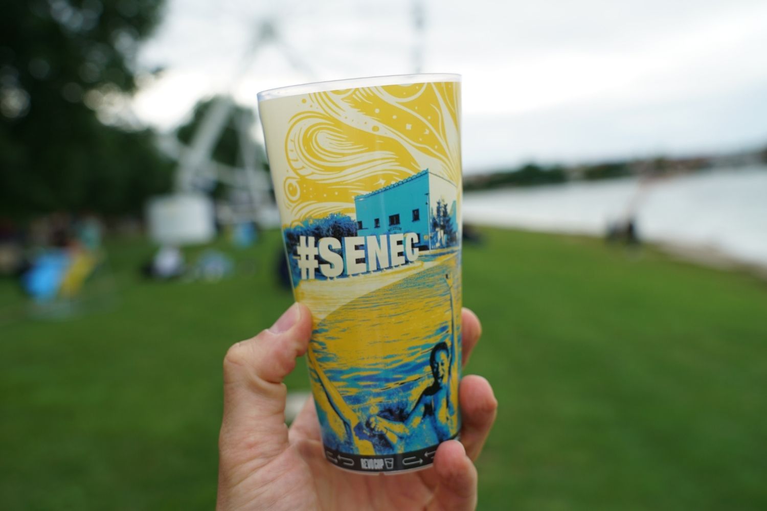 Reusable Senec festival cup held by the lake.
