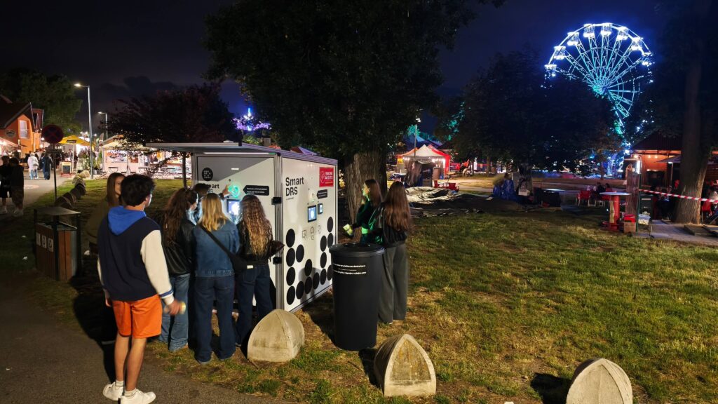 Návštevníci využívajúci automatizovaný systém Smart DRS na vrátenie opakovane použiteľných pohárov počas letného festivalu Senecké leto na Slovensku.