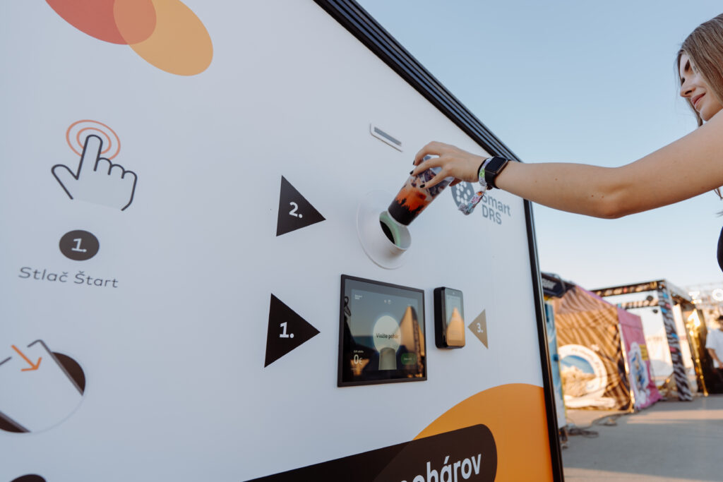 Festival visitor inserting a reusable cup into a Smart DRS return station