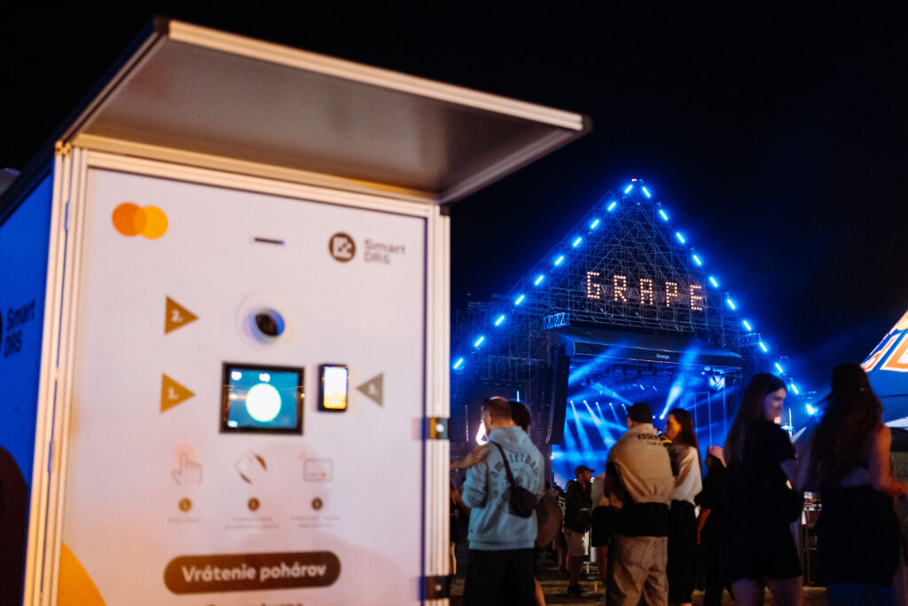 Smart DRS reusable cup return station beside an illuminated festival stage at night