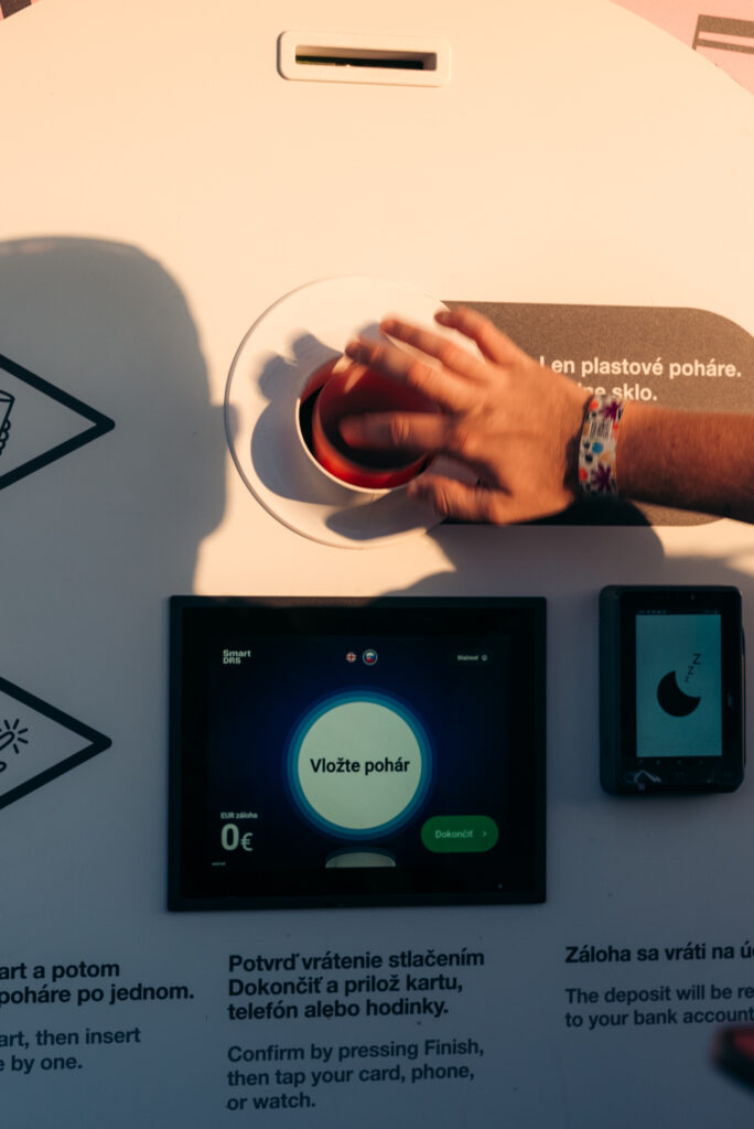 Close-up of a festival visitor inserting a reusable cup into a Smart DRS automated return station
