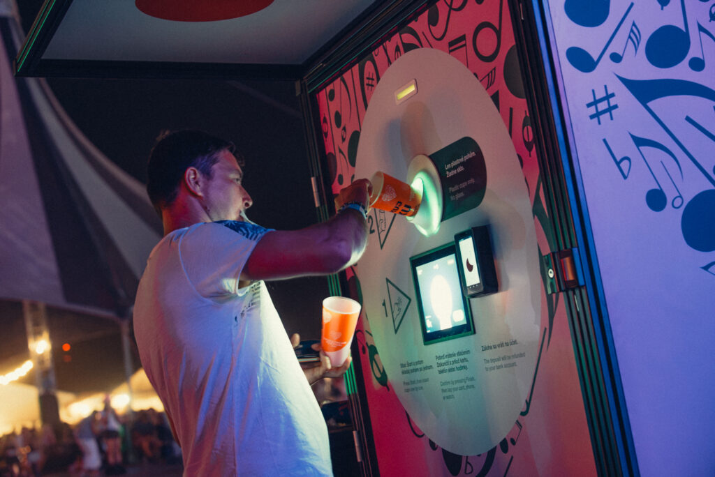 Festival visitor inserting a reusable cup into a Smart DRS automated return station