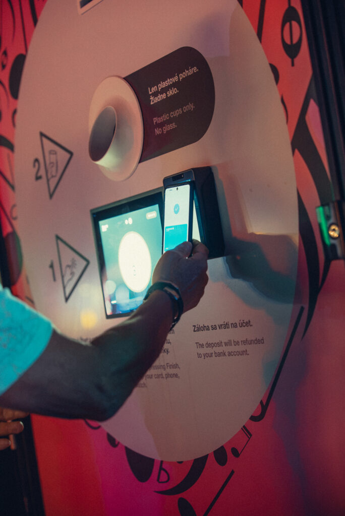 Festival visitor tapping a mobile phone at a Smart DRS return station to receive a reusable cup deposit refund at LOVESTREAM Festival 2026.