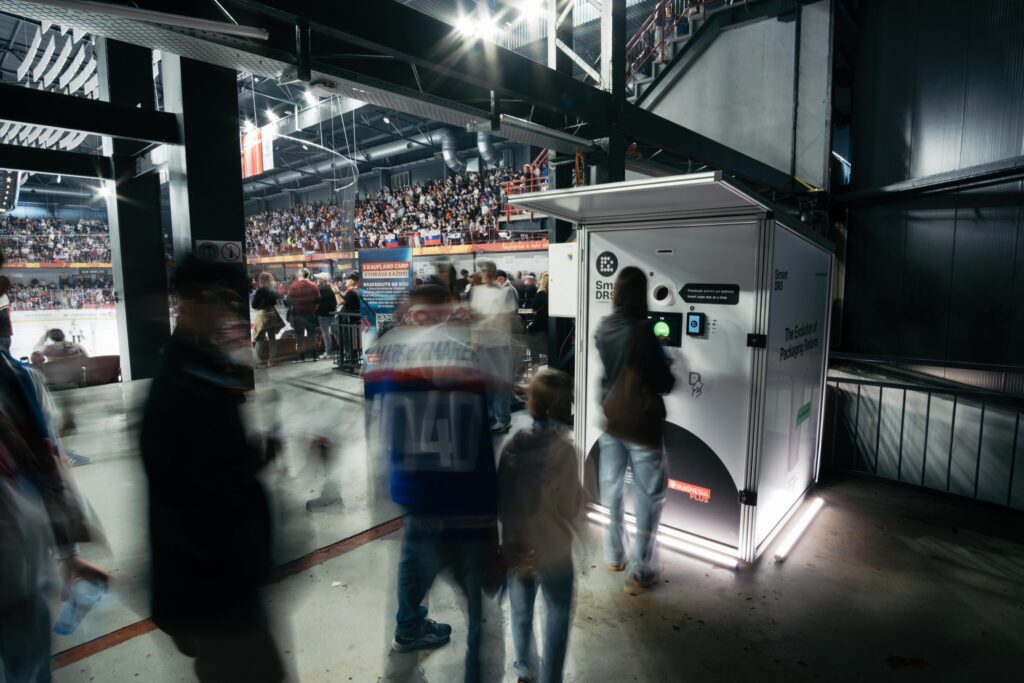 Visitors using a Smart DRS reusable cup return station at a crowded sports arena